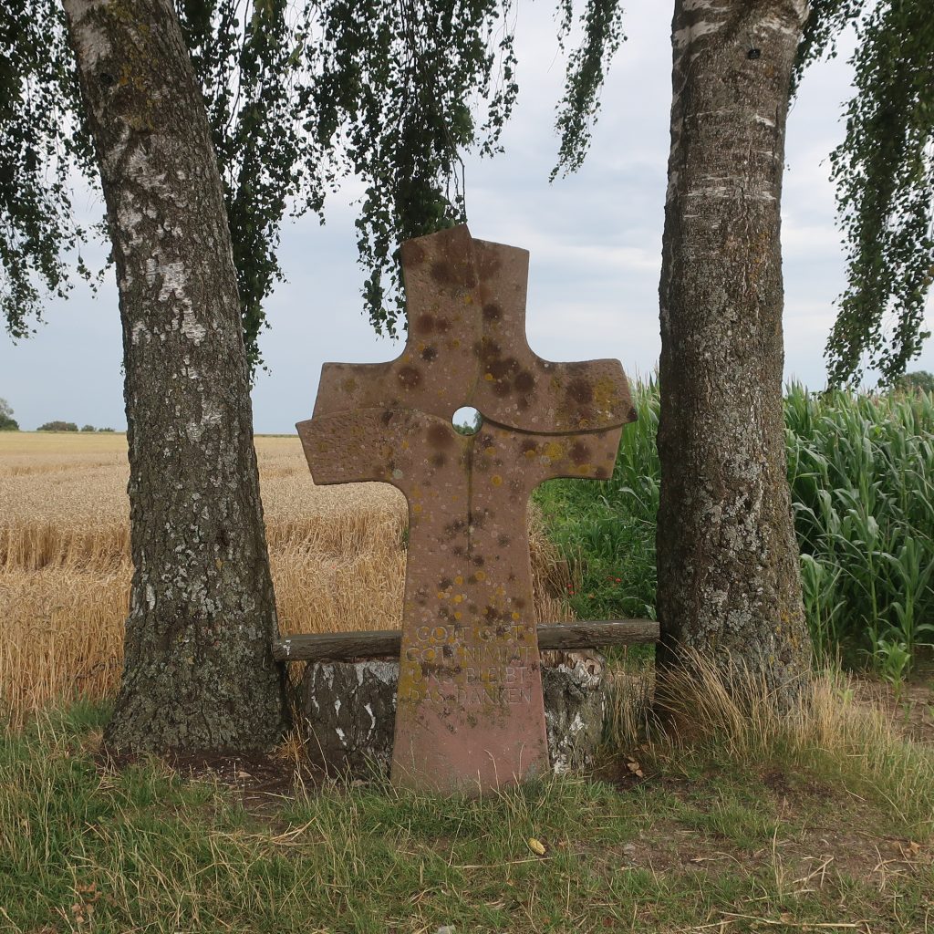 Steinkreuz zwischen zwei Birken.